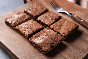 Wooden board with pieces of tasty chocolate brownie on table