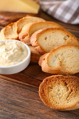 Tasty croutons with sauce on wooden background