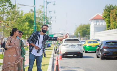 Three South Asian tourists with cameras happily hitchhiking the road behind Wat Pho during their long weekend happily. in Bangkok, Thailand