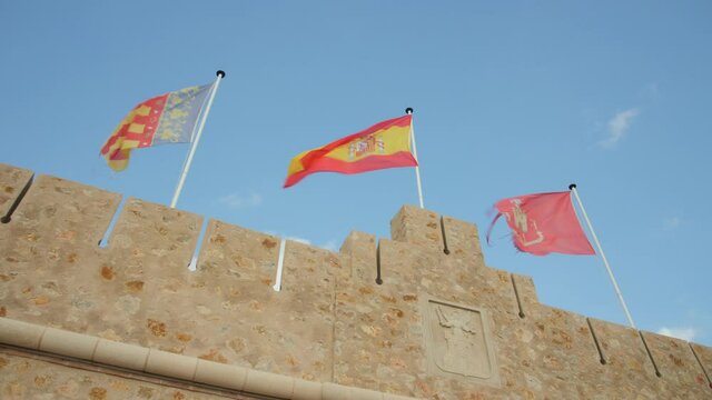 Spanish Flags Swaying On Gentle Breeze On Segorbe Castle In Spain. low angle