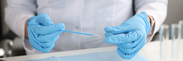 Doctor in gloves holds brush for smears and glass in laboratory