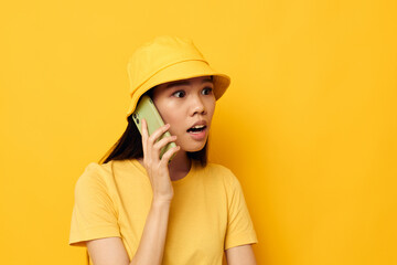 Portrait Asian beautiful young woman in a yellow hat and T-shirt talking on the phone Lifestyle unaltered