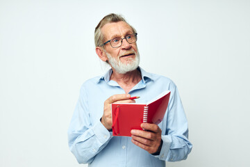 Portrait elderly man writes down emotions in a notebook light background