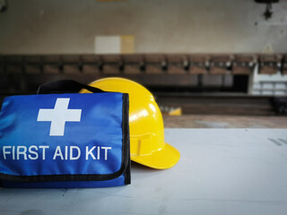 Safety at work concept. Helmet and first aid kit bag on the table.