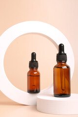 Amber glass dropper bottles on geometrical round form on beige background. Cosmetic container mock-up. Background for branding and packaging presentation. Natural skincare beauty product concept.