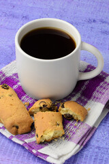 Black coffee in a white mug and pieces of homemade cookies with raisins on a colored background. Tasty breakfast. Side view. Vertical image.