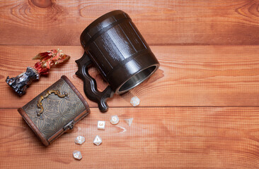 Ivanovo, Russia - 02.11.2021: Set of role playing white dices, stylized beer mug, toy miniature of dragon and storage box for playing Dungeons and Dragons role-playing, top view on wooden background