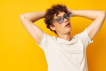 portrait of a young curly man in a white t-shirt blue fashion glasses isolated background unaltered