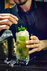 a bartender putting the finishing touches to a tasty freshly made mojito cocktail by adding straws