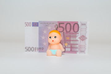 500 five hundred cash money miniature newborn infant baby toy sitting on a white gray background.Selective focus,copy space.