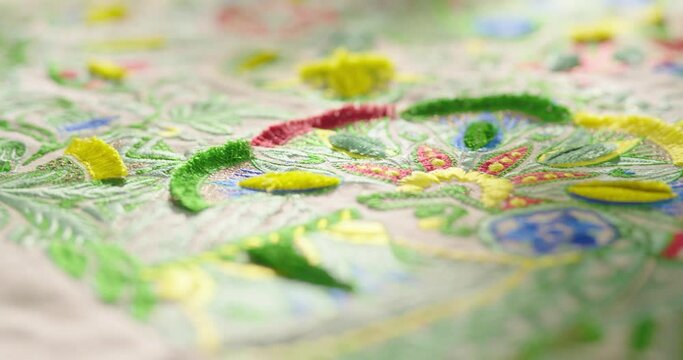 Close up pan shot of colorful sewed pattern on table cloth in fabric