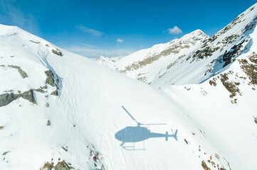 Helicopter shadow projected onto snow on mountains