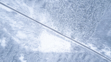Aerial top down drone shot of Snowy forest and empty road. Forest road from above
