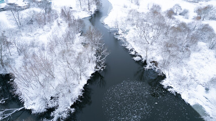 Aerial top down drone shot of Snowy nature and river. Forest road from above