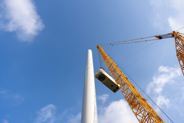 Construction of a wind power generator for renewable energy, Turbine hangs on crane hook at wind...