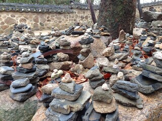 돌담과 기와, 소원돌이 쌓인 절 풍경 / A temple with stone walls, tiles, and wish stones.