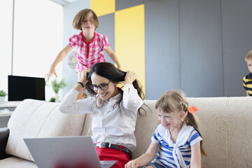Obraz premium Happy woman working and playing with her kids on couch