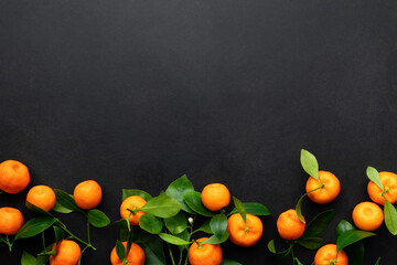 Mandarins or clementines with leaves on a black background. Top view.
