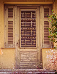 Fototapeta na wymiar old weathered olive green painted door and double linear window shutters