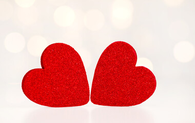 two red hearts on a light background with bokeh