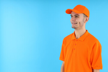 Attractive young delivery man on blue background