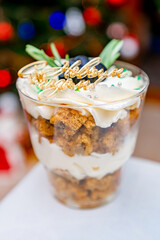 Christmas trifles cakes in a glass on the background of a Christmas tree with a garland