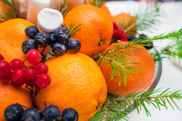 Christmas composition of mandarins and fir twigs with berries on the festive table