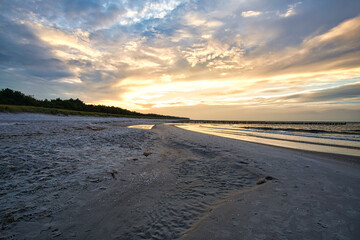 sunset on the baltic coast with clouds in the sky and reflections in the water.