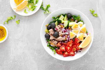 Tuna and fresh vegetable salad of tomato, cucumber, olives, onion, lettuce and boiled egg, top view