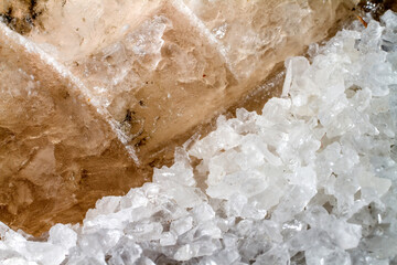 Granular salt on the background of a block of rock salt.