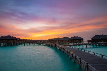 Fototapeta na wymiar Amazing sunset panorama at Maldives. Luxury resort villas seascape with soft led lights under colorful sky. Dramatic twilight sky and colorful clouds. Beautiful beach background for vacation holiday