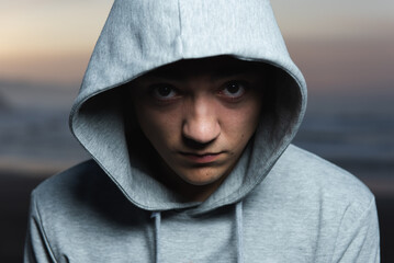 Dramatic portrait of serious hispanic teenager looking to the camera and wearing a hoodie.