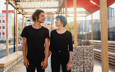 Young guy and  girl hold hands, look into each other's eyes against the background of the street. Love, gender relations concept.