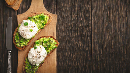 Avocado toast with poached egg on cutting board with copy space top view