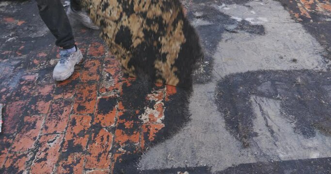 Workers remove the deteriorated bituminous sheath attached to the floor of a building's terrace. Then a new waterproofing layer will be placed.
