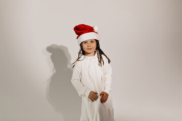 Lovely charming girl wearing white dress and Santa cap having fun over isolated background. Holiday concept