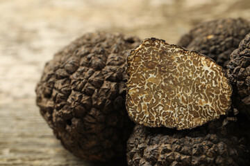 Heap of whole and cut black truffles on table, closeup