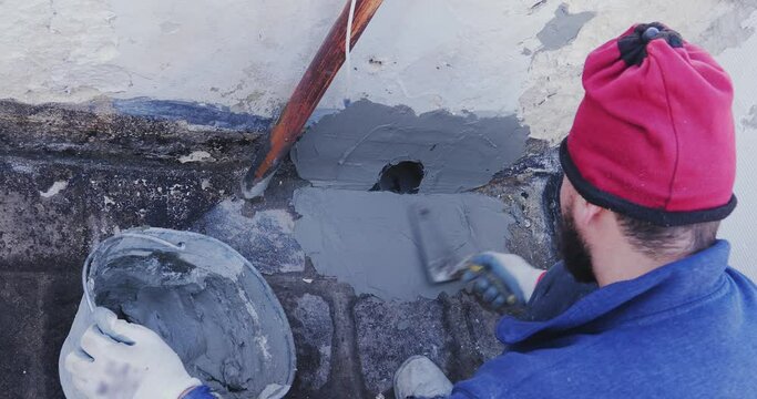 Worker places a PVC sleeve with quick-setting mortar for draining rainwater from a flat terrace.