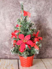 a small Christmas tree in a pot decorated with flowers