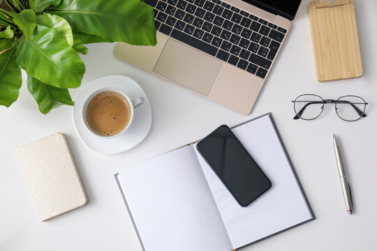 Office stationery, laptop and smartphone on white table, flat lay