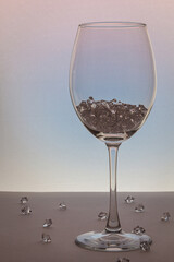 Wine glass, with ice cubes on white. Concept of precious stones in glass. Pieces of ice are scattered over the background
