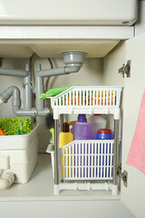 Different cleaning tools and supplies in open cabinet under sink