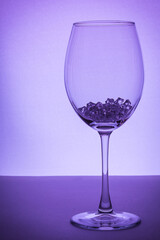 Very Peri. Wine glass, with ice cubes on white. Concept of precious stones in glass. Glass beads, gems in glass. Jewelry, copy space, selective focus, low key