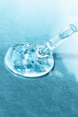 Dropper with hyaluronic acid close-up on a blue background. Drop of cosmetic product top view. Textured transparent gel used in beauty.