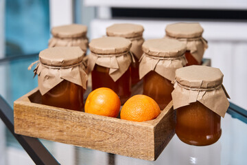 homemade caramel is poured into jars, stands on a transparent table in a wooden stand