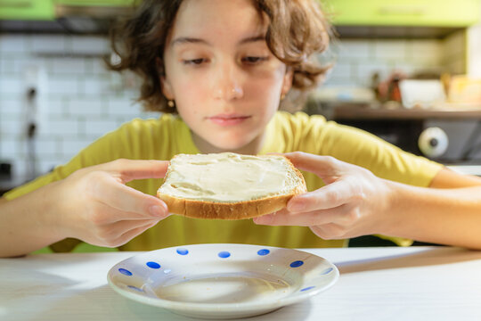 Teenage Girl Eating Snack Of Toaster Bread With Cheese Or Butter