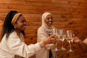 Diverse friends toasting with drinking glasses in a cafe