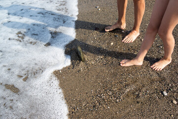 children's bare feet on wet rocks and in sea foam