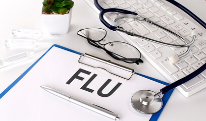 FLU text on white paper on white background. stethoscope ,glasses and keyboard