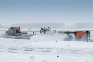 Two snowblowers cleans airport taxiway in a blizzard